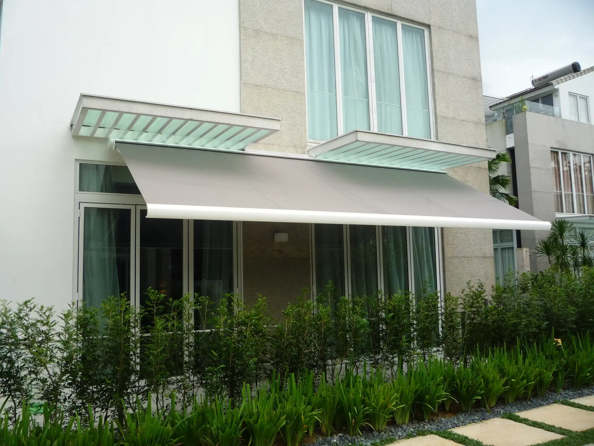 Motorized cassette awning with protective housing mounted on a wall