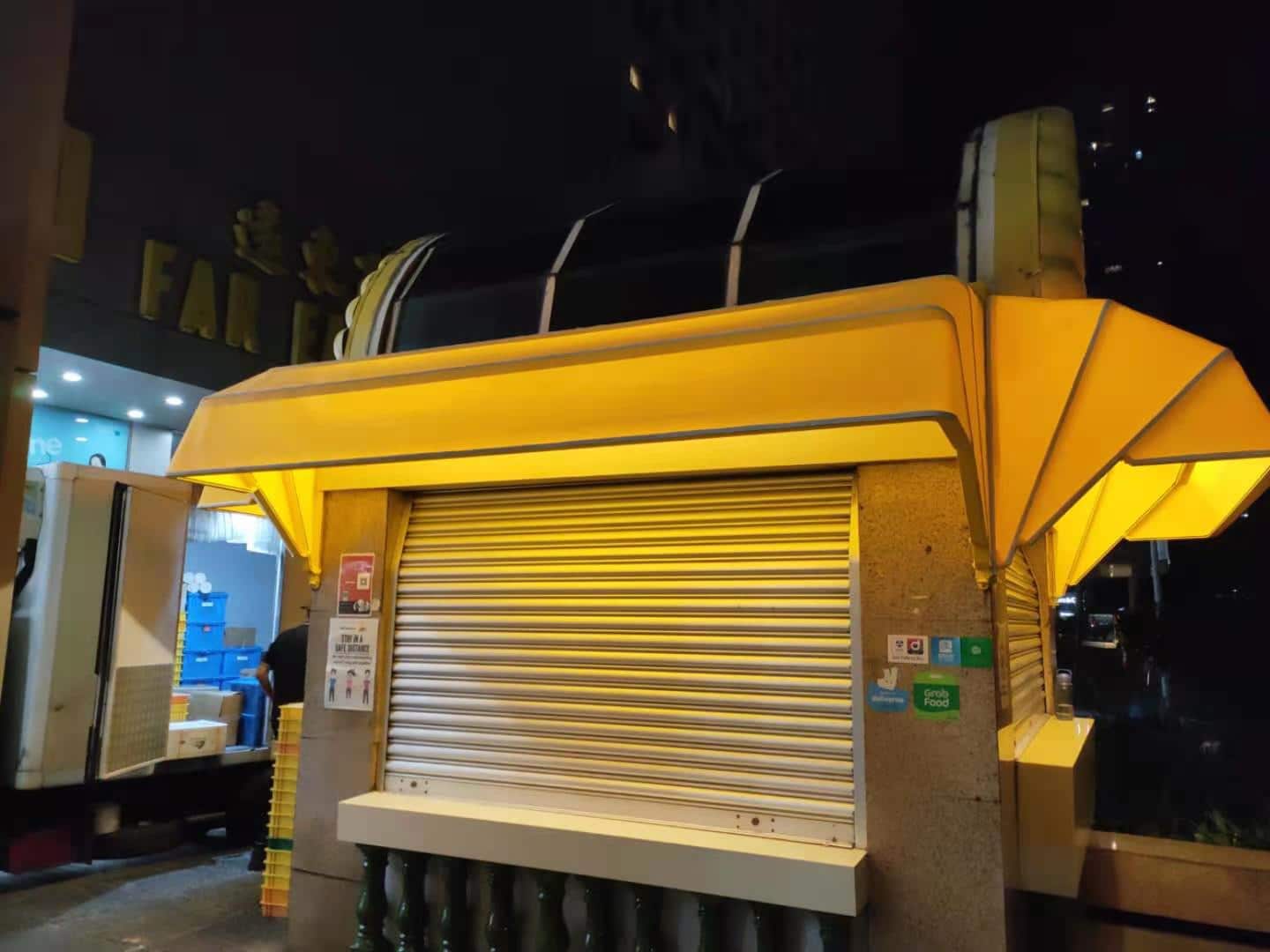 Retractable canopy with warm yellow lighting over a closed kiosk in Singapore