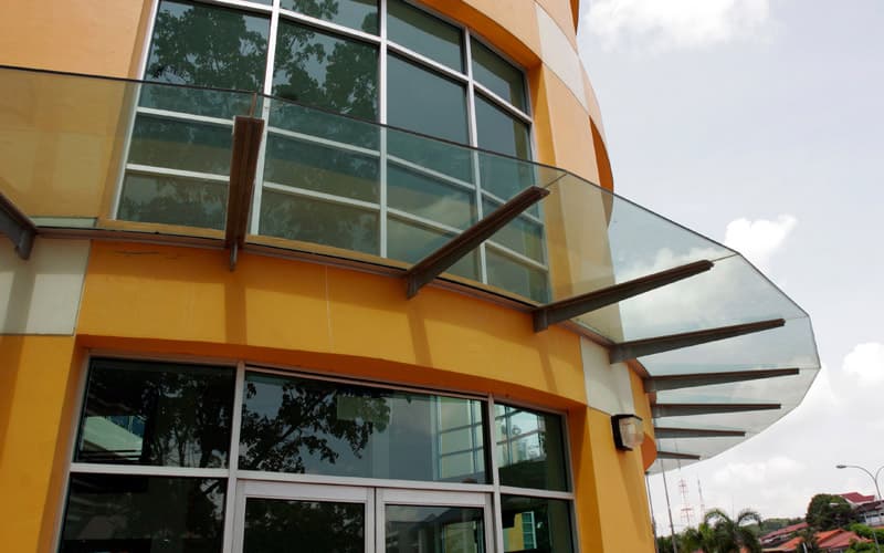 Tempered glass awning providing rain protection outside a building in Singapore